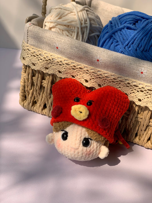 BTS V crochet keychain in front of a basket with yarn balls